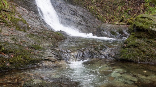 The bottom of a wintry looking Whitelady Waterfall flowing into the clear water of the pool below